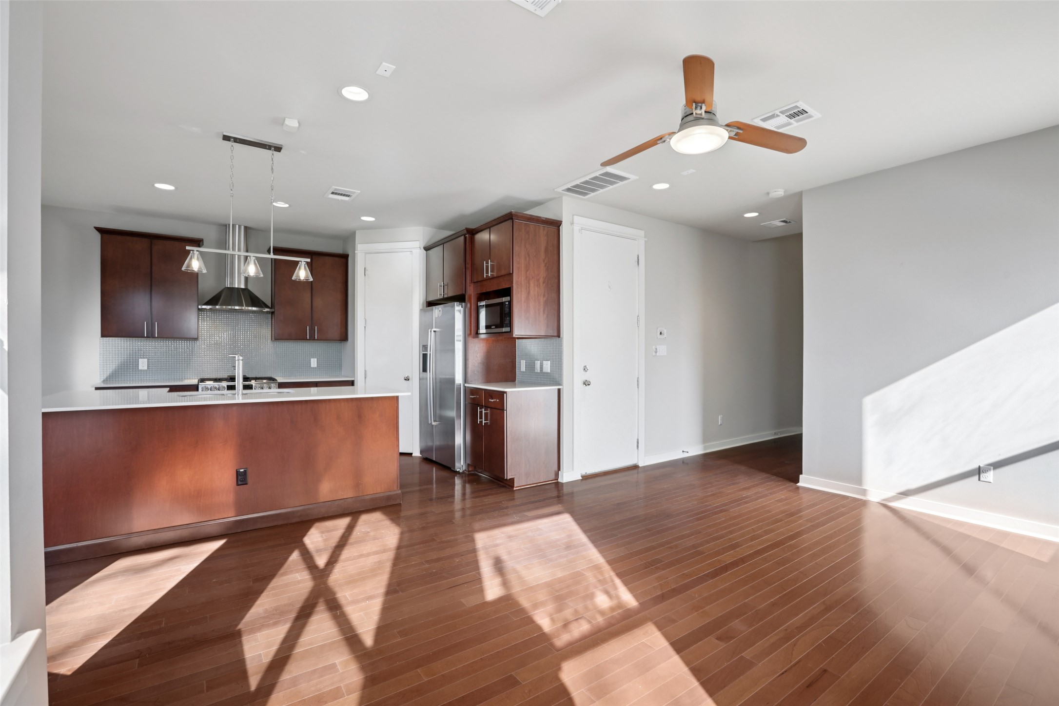 1123 Blair Way Austin, TX 78704 - Photo 29 of 30 Kitchen with light countertops, open floor plan, decorative light fixtures, wall chimney range hood, and tasteful backsplash