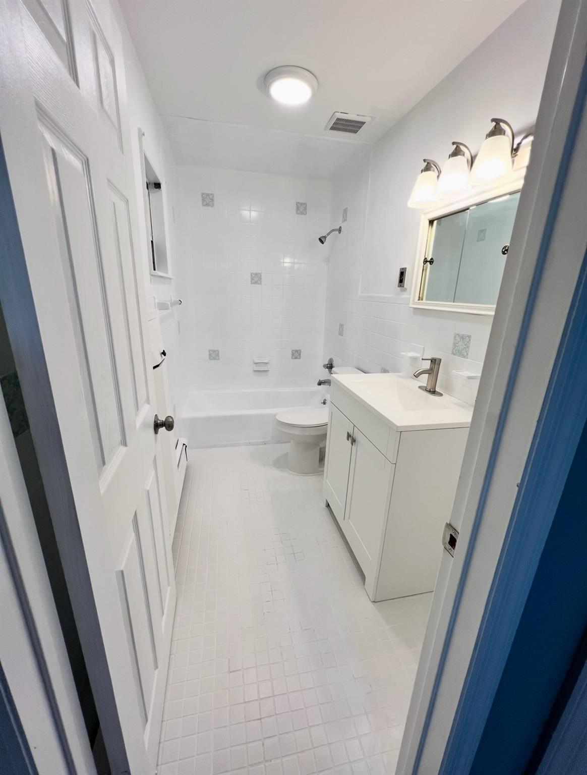 2410 Boston Post Road Larchmont, NY 10538 - Photo 20 of 26 Full bathroom featuring toilet, tiled shower / bath combo, tile patterned flooring, tile walls, and vanity