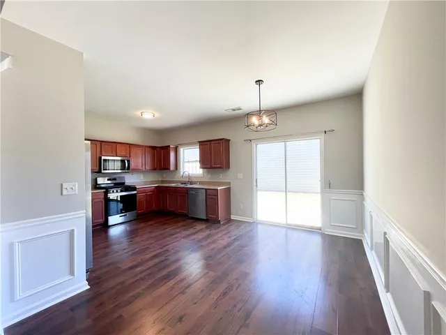 a living room with stainless steel appliances kitchen island hard wood floors and fireplace