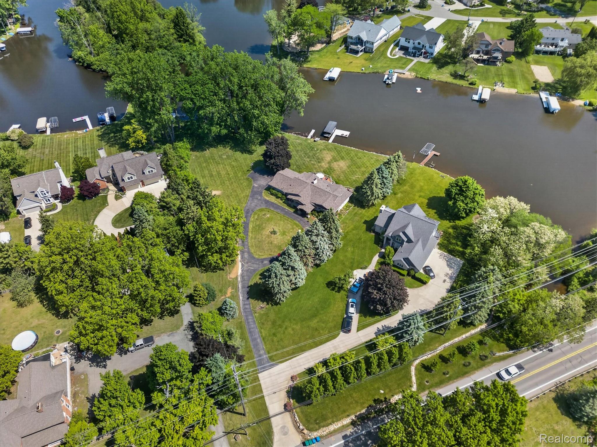 3860 East Commerce Road Commerce Township, MI 48382 - Photo 68 of 72 Expansive waterfront property featuring a large residence with a multi-car driveway, substantial green space, mature trees, and direct water access with a private dock
