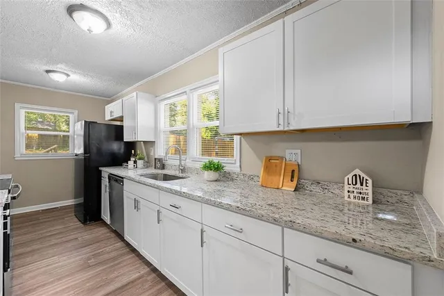 a kitchen with granite countertop a sink a stove cabinets and wooden floor