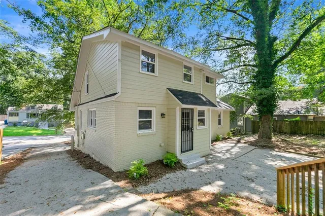 a view of a grey house with a large windows and large tree