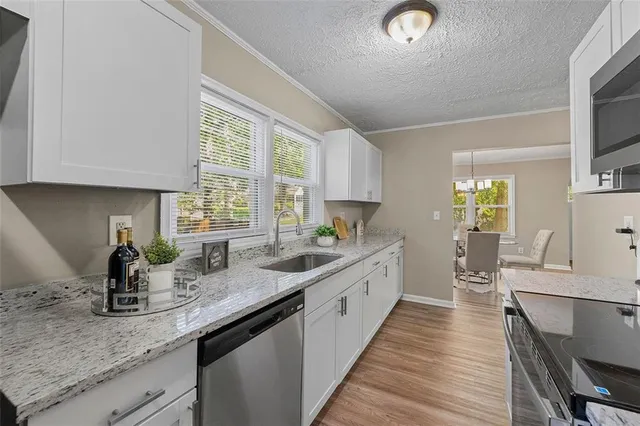 a kitchen with granite countertop a sink appliances cabinets and a counter top space