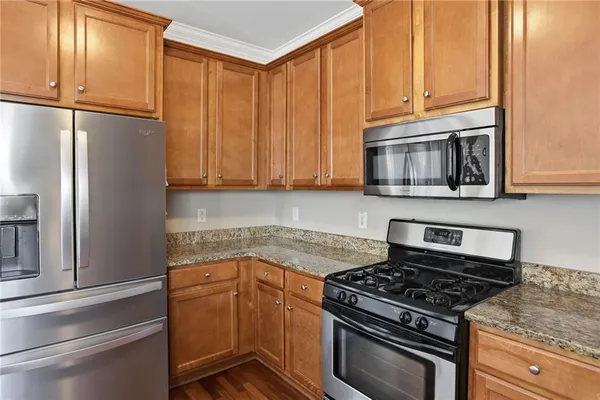 a kitchen with granite countertop a refrigerator stove and microwave