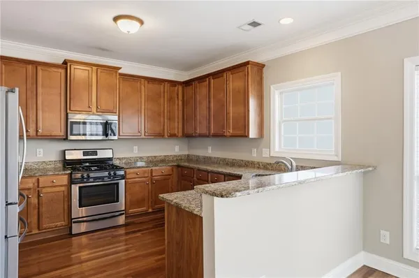 a kitchen with stainless steel appliances granite countertop a stove a sink and a microwave