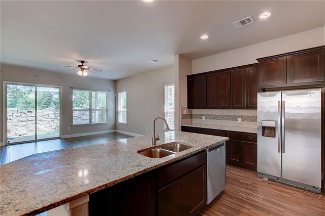 a kitchen with stainless steel appliances granite countertop a sink a stove and a refrigerator