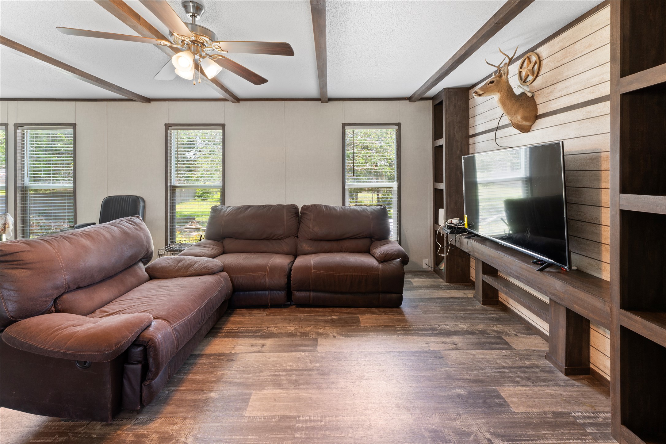 109 Hibiscus Cove Elgin, TX 78621 - Photo 3 of 15 A comfortable living space boasts a ceiling fan, plank flooring, and multiple windows for natural illumination.