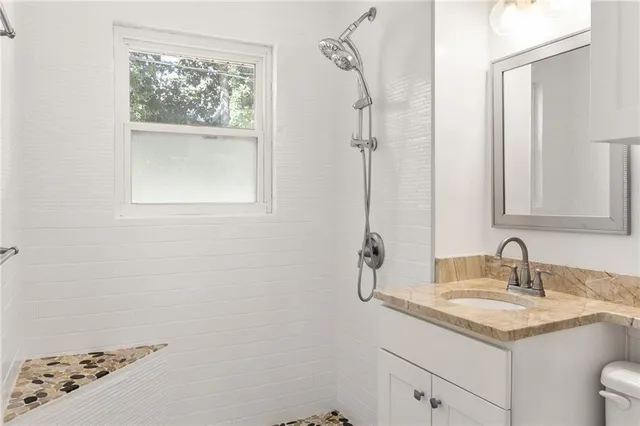 a bathroom with a granite countertop sink a mirror and a shower