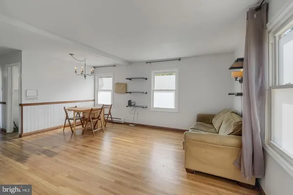 a living room with furniture and a dining table with wooden floor