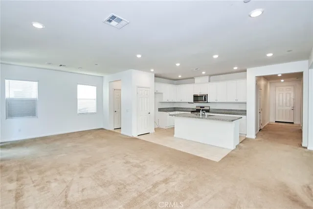 a view of kitchen with kitchen island white cabinets and refrigerator