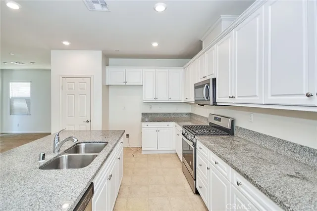 a kitchen with granite countertop a sink stove and cabinets