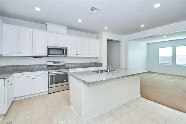 a kitchen with stainless steel appliances granite countertop a sink and dishwasher a stove top oven with white cabinets