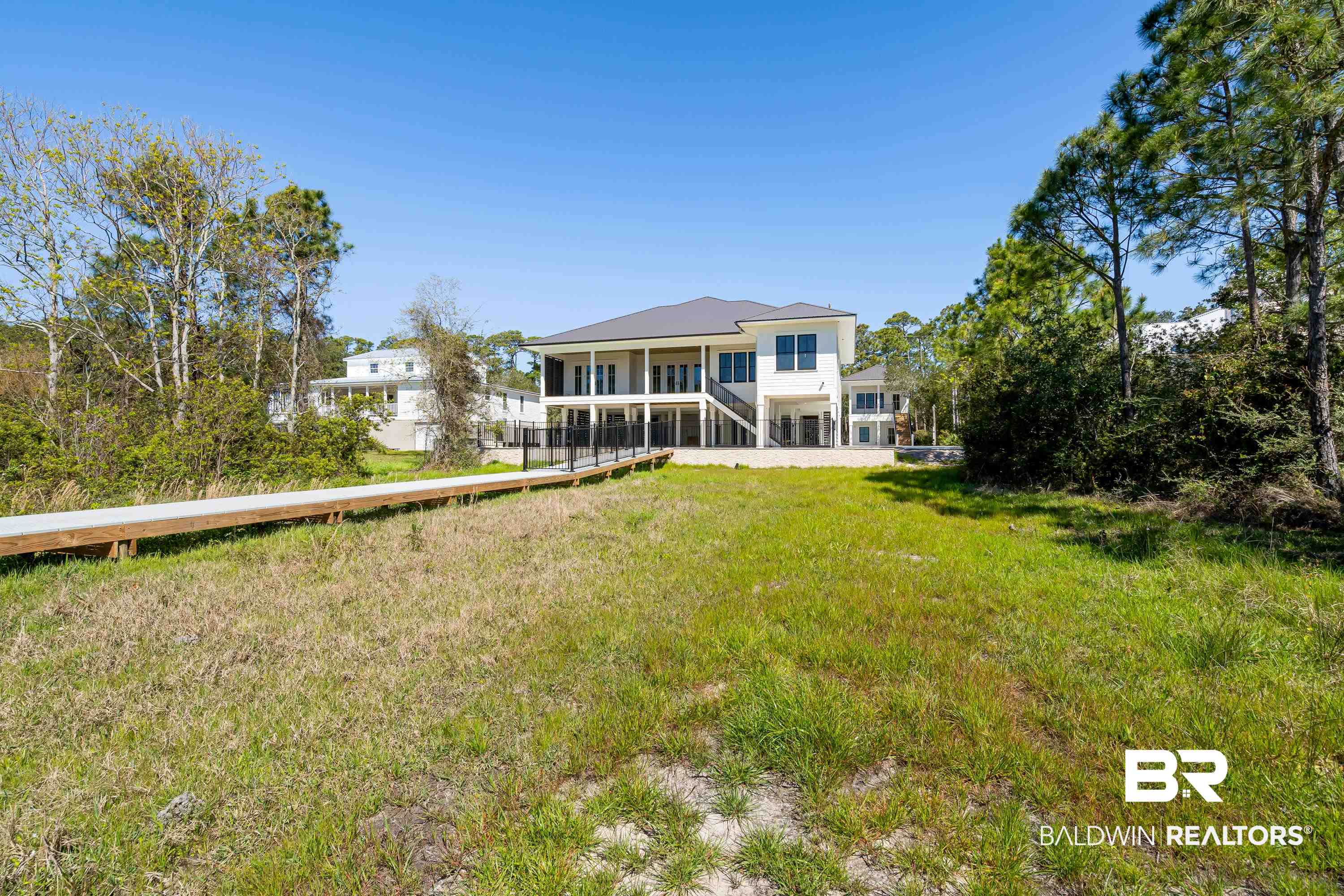 14686 State Highway Gulf Shores, AL 36542 - Photo 32 of 44 Back of property with a lawn, a sunroom, and stairway