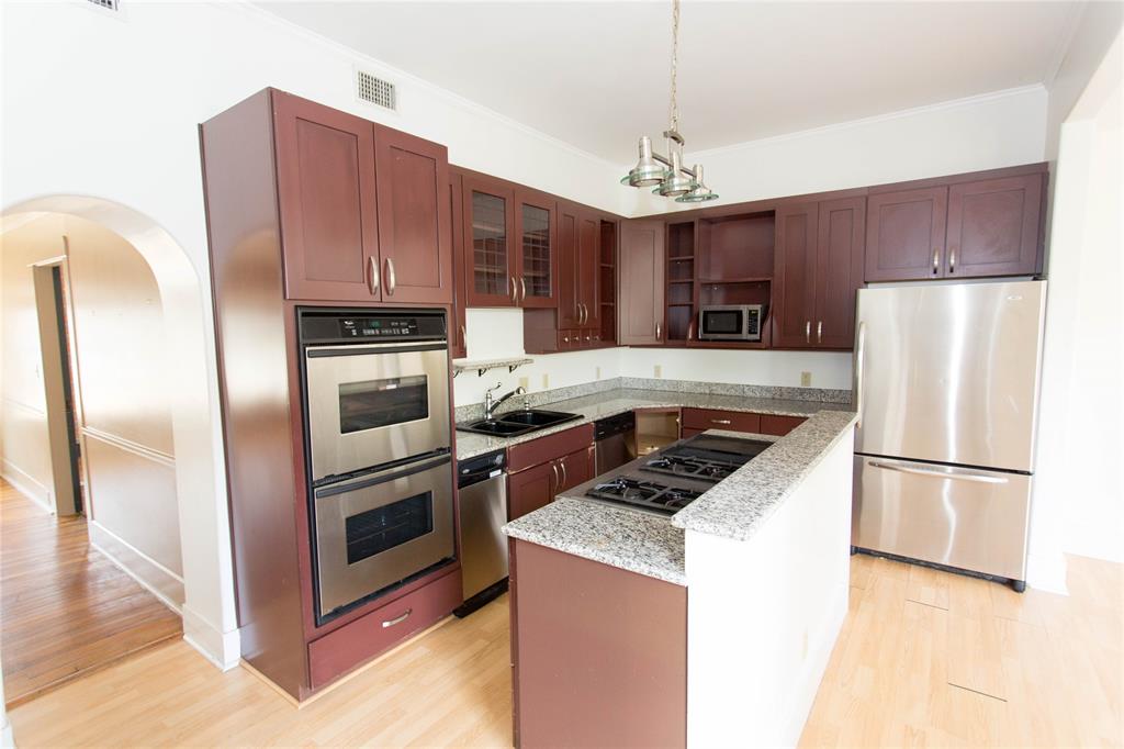 201 West 33rd Street, Unit A Austin, TX 78705 - Photo 7 of 20 a kitchen with kitchen island granite countertop stainless steel appliances a refrigerator a stove a sink cabinets and a center island
