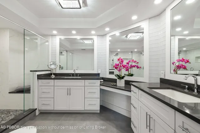 a bathroom with a granite countertop sink a large mirror and a shower