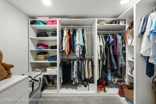 a view of walk in closet with clothes and shoes