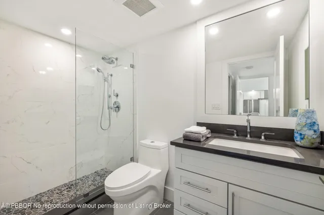 a bathroom with a granite countertop sink a toilet a mirror and shower
