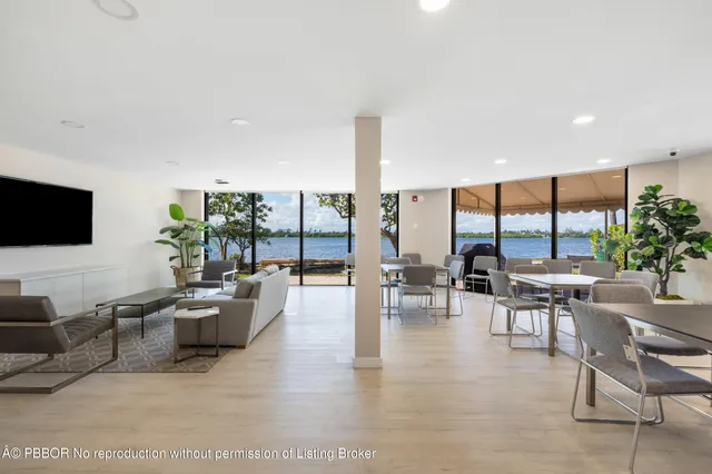 a living room with furniture floor to ceiling window hardwood floor and a flat screen tv