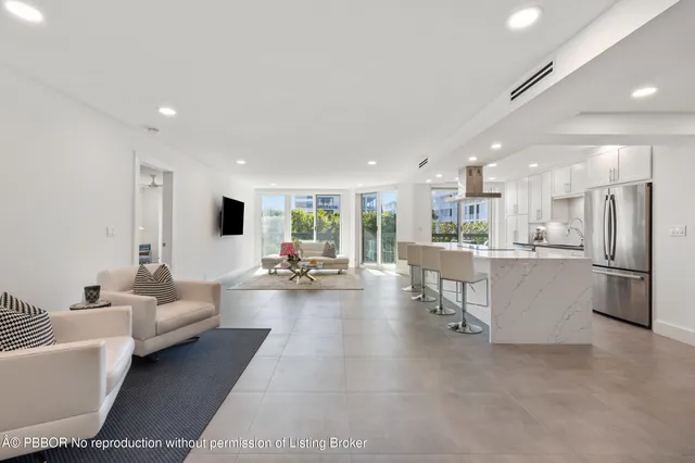 a living room with couches and kitchen view with wooden floor