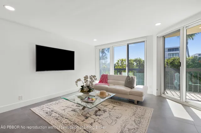 a living room with furniture a flat screen tv and a floor to ceiling window