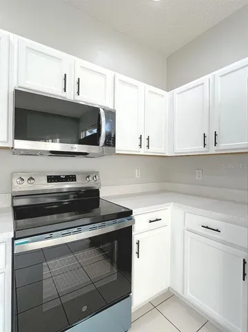 a kitchen with granite countertop white cabinets and appliances