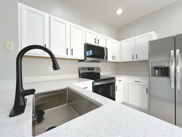 a kitchen with granite countertop a stove and white cabinets