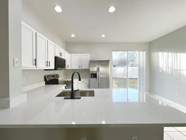 a kitchen with kitchen island a counter top space a sink stainless steel appliances and cabinets
