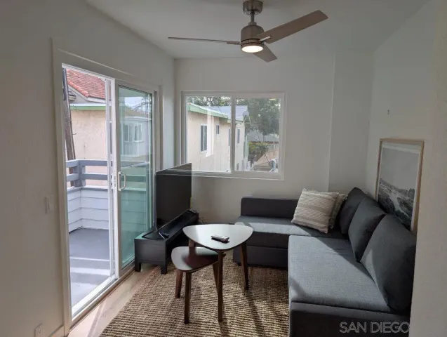 a living room with furniture a flat screen tv and a window