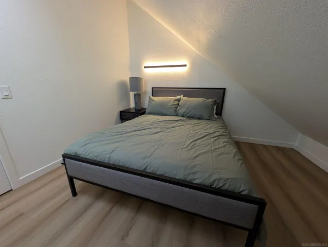 a bedroom with a bed and wooden floor