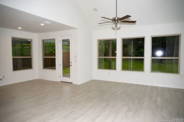 a view of an empty room with a window and wooden floor