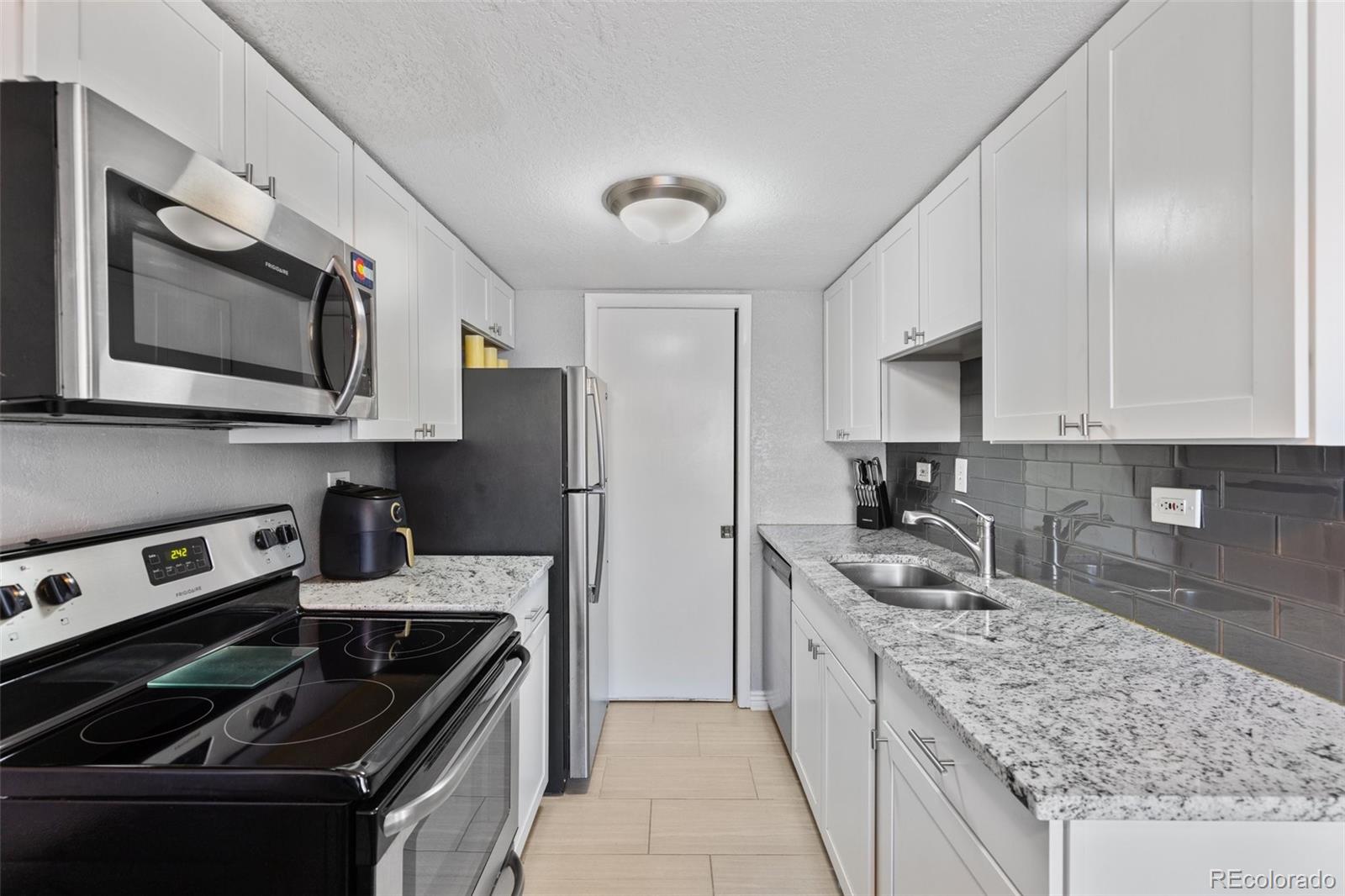 200 Pearl Street, Unit 106 Denver, CO 80203 - Photo 2 of 16 a kitchen with stainless steel appliances granite countertop a sink stove microwave and cabinets