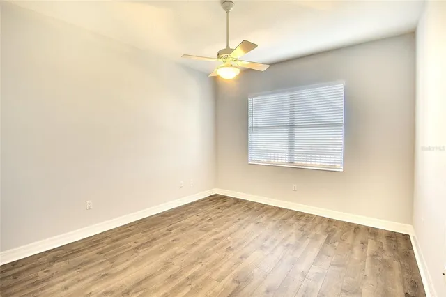 an empty room with wooden floor fan and window