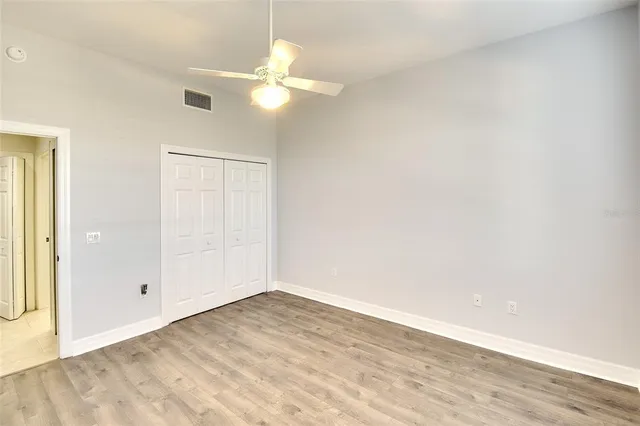 an empty room with wooden floor fan and window
