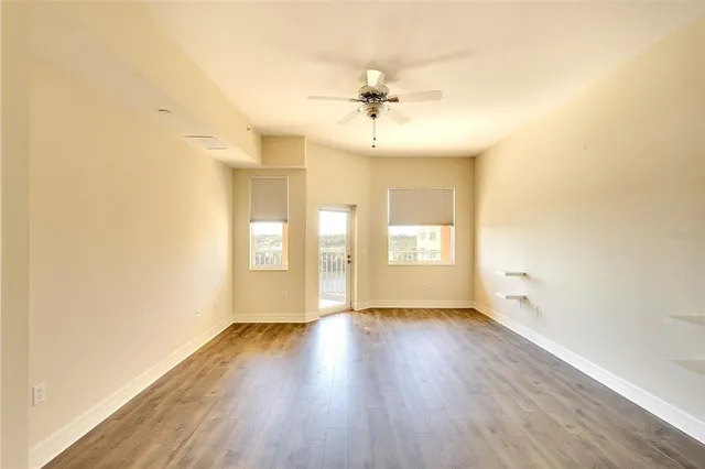a view of an empty room with wooden floor and a window
