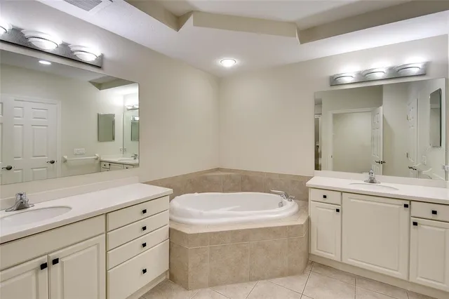 a bathroom with a tub double vanity sink and mirror