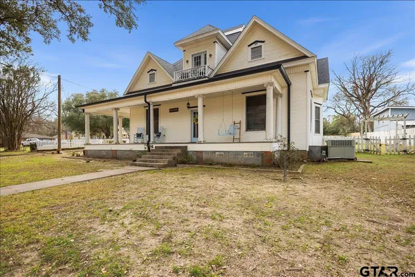a view of a white house with a large space in front of it