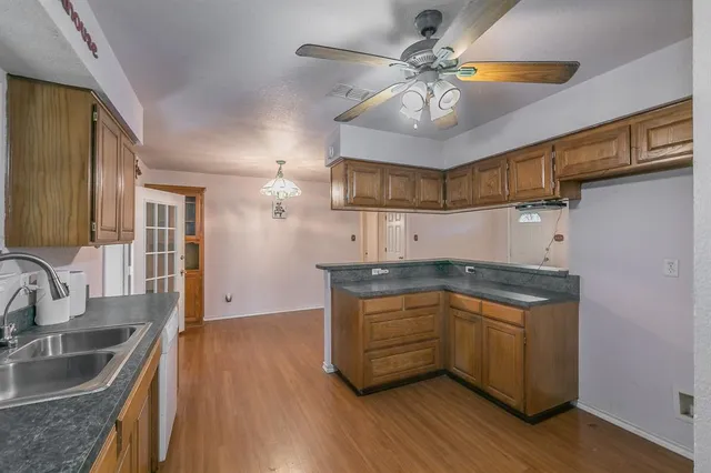 a kitchen with stainless steel appliances granite countertop a sink a stove cabinets and wooden floor