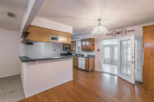 a kitchen with stainless steel appliances a sink a stove a refrigerator cabinets and a wooden floor