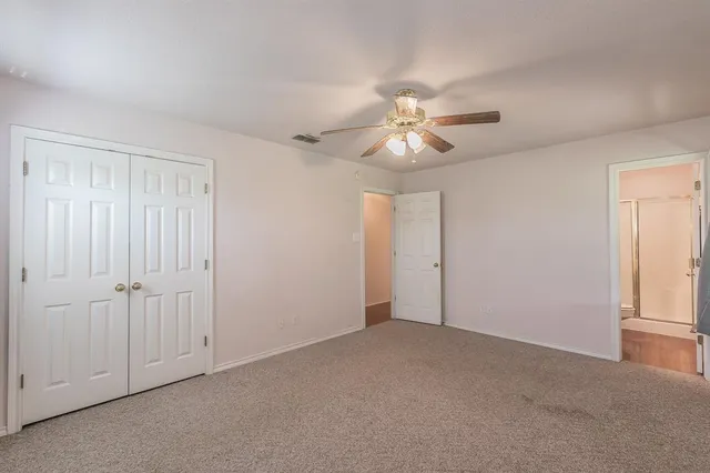 an empty room with chandelier fan and windows