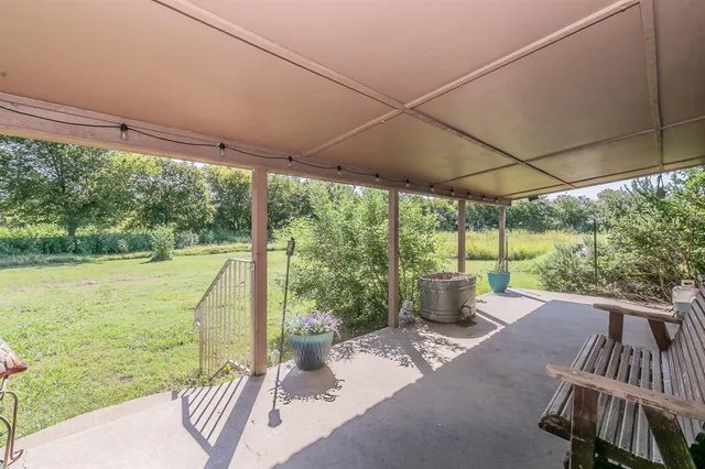 a view of a patio with lawn chairs next to a yard