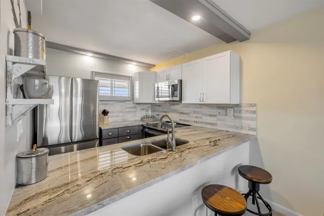 a kitchen with stainless steel appliances granite countertop a sink refrigerator and cabinets