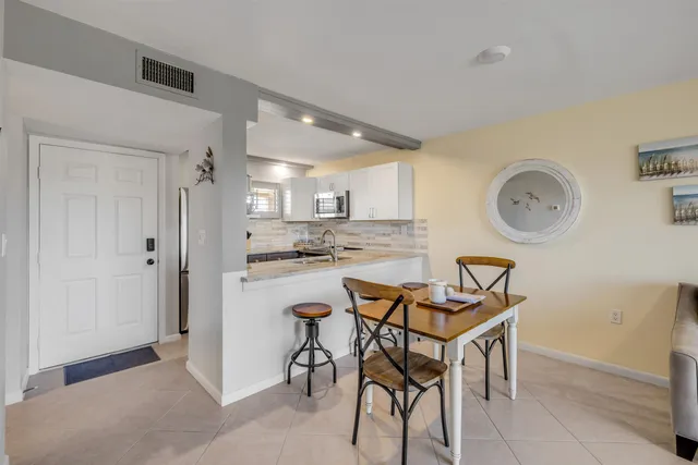 a kitchen with stainless steel appliances granite countertop a dining table chairs and a refrigerator