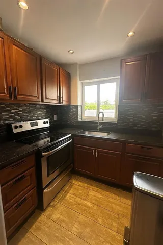 a kitchen with stainless steel appliances granite countertop a stove a sink and a microwave