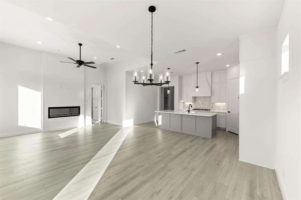 1105 Birdsong Trail Anna, TX 75409 - Photo 13 of 27 a large kitchen with white cabinets a sink dishwasher a dining table and chairs with wooden floor