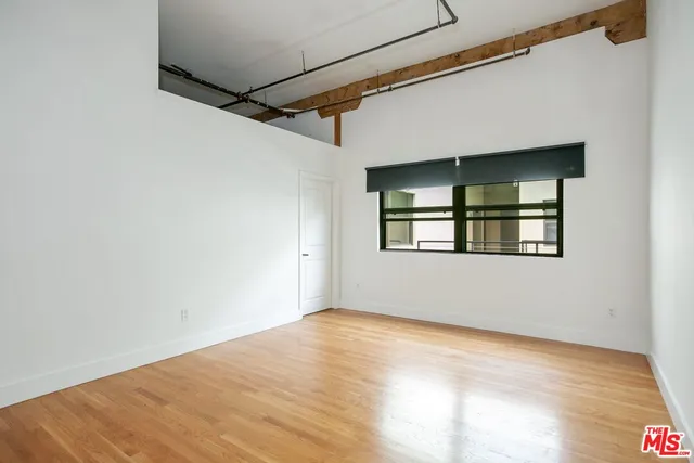 a view of an empty room with wooden floor and windows