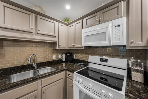 a kitchen with granite countertop white cabinets stainless steel appliances and sink