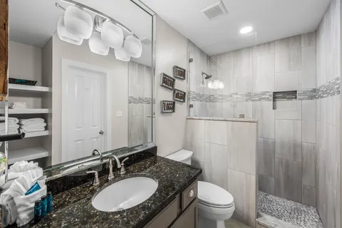 a bathroom with a granite countertop sink toilet a mirror a vanity and shower