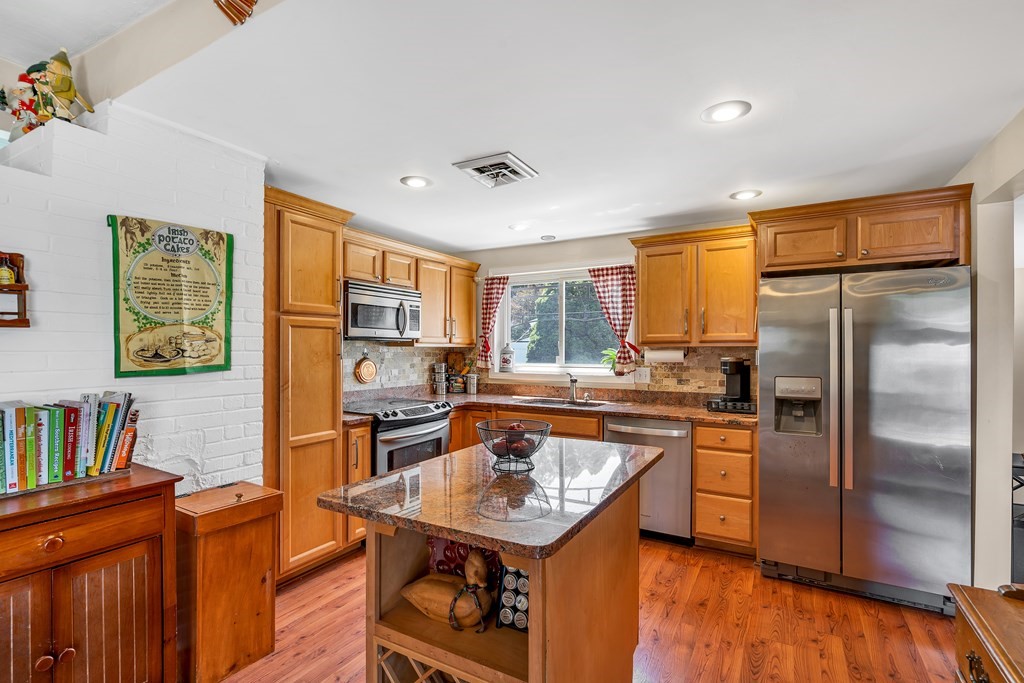 7 Leonard Road Framingham, MA 01701 - Photo 6 of 27 a kitchen with stainless steel appliances granite countertop a refrigerator a sink dishwasher a stove and a dining table with wooden floor