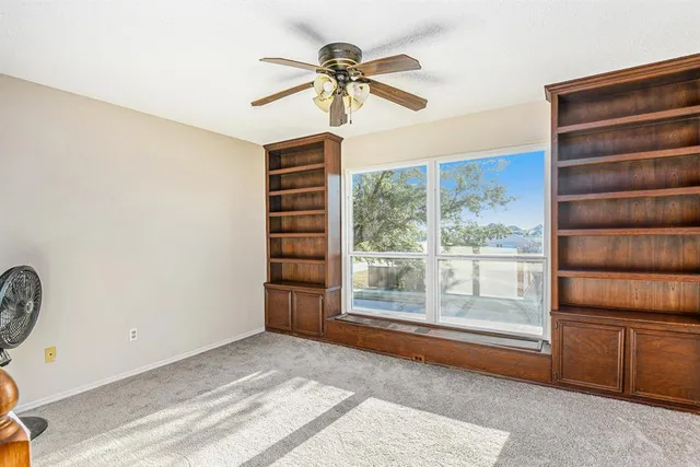 an empty room with windows and ceiling fan view