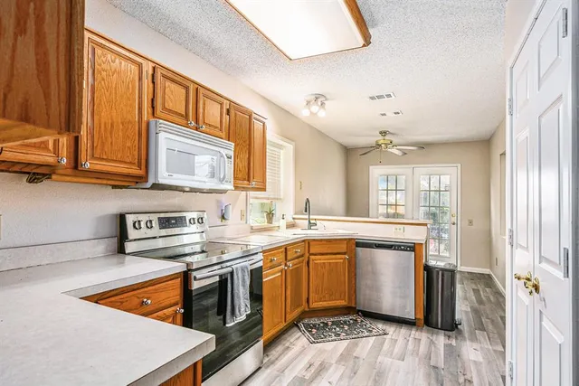 a kitchen with stainless steel appliances granite countertop wooden cabinets a sink and dishwasher a stove with wooden floor